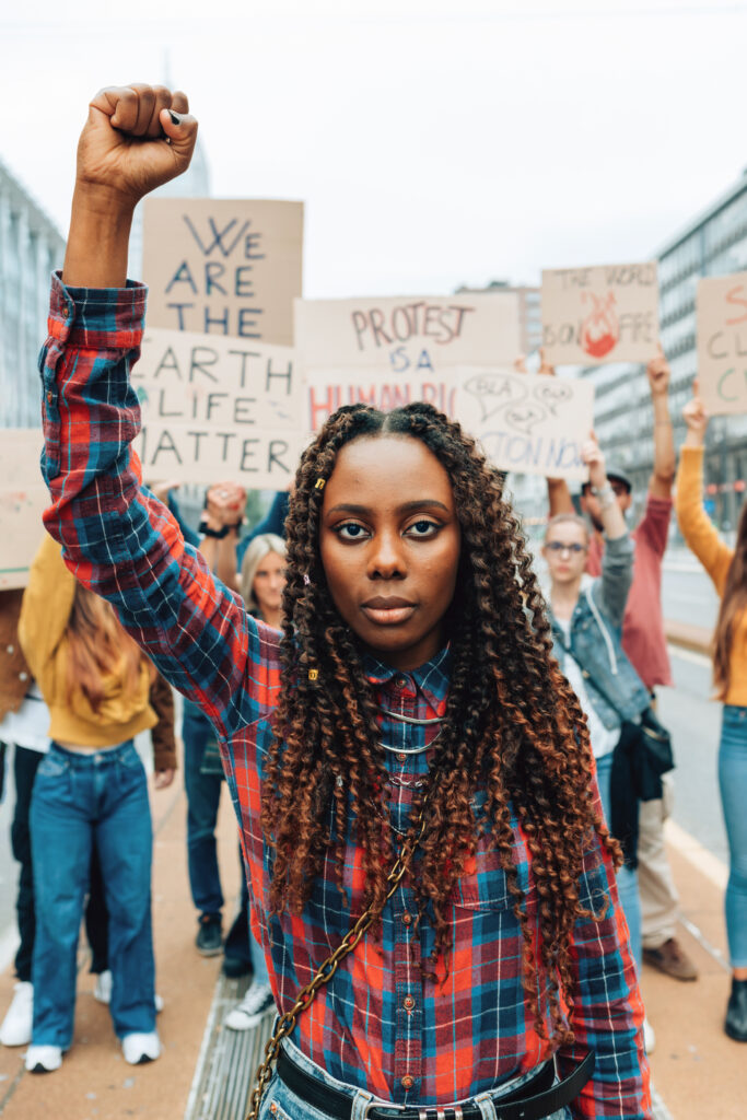 portrait-of-african-american-young-woman-with-raised-fist-at-street-demonstration-for-climate-vertical-picture-social-justice